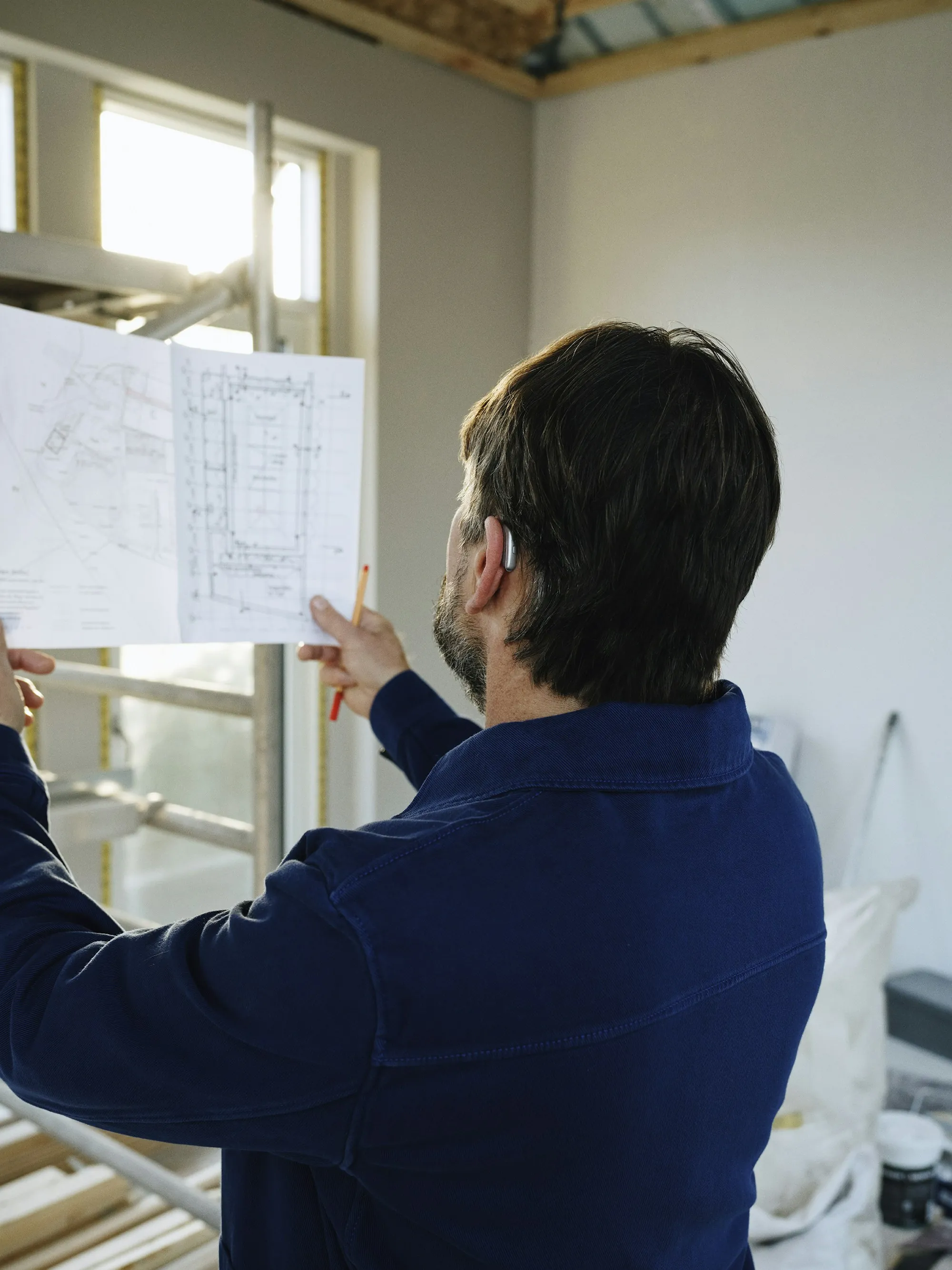 Remodeling crew member measuring a framed basement wall
