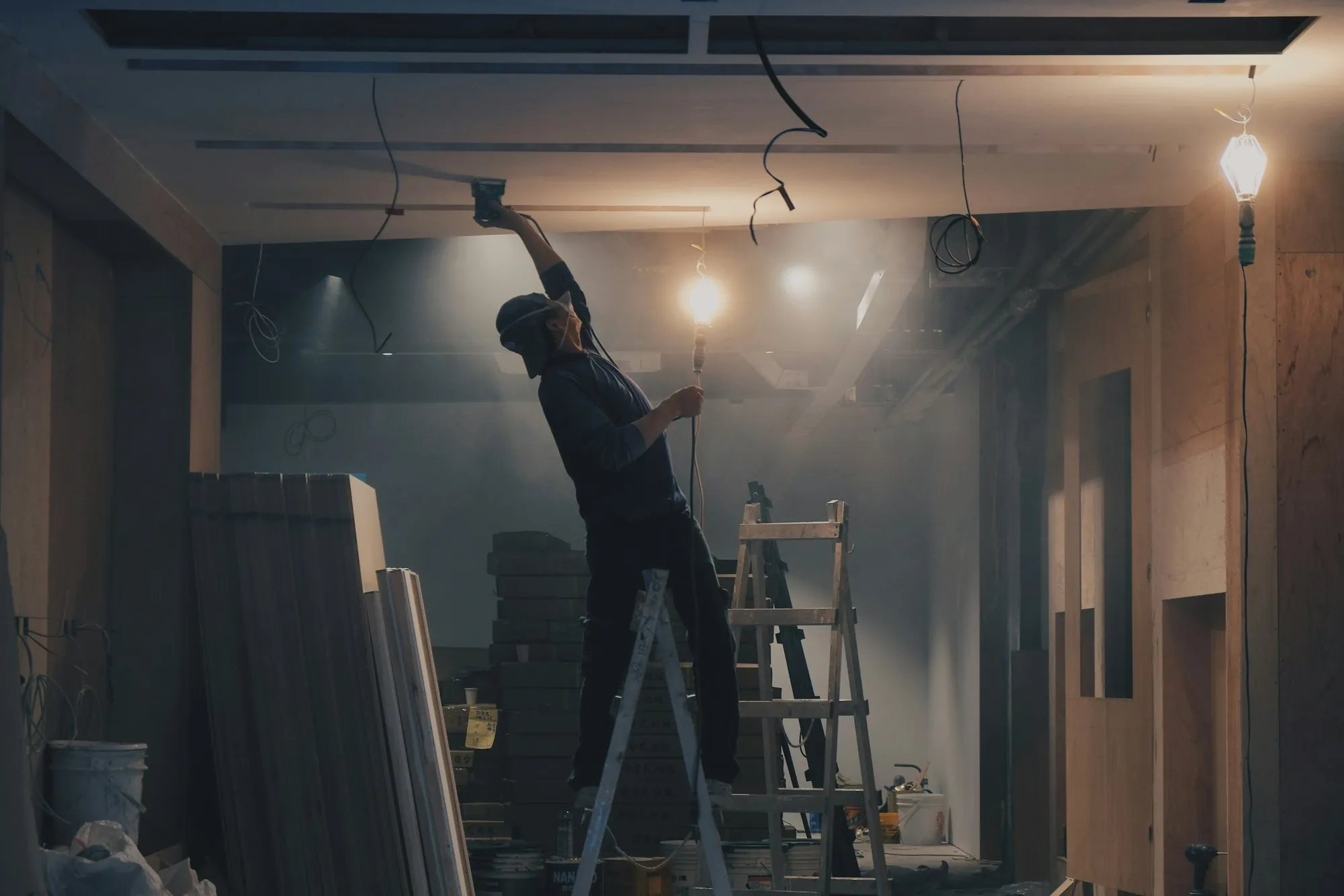 Worker on a ladder finishing the ceiling inside a newly framed addition